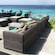A seating area with couches, chairs, pillows and tables on a beach